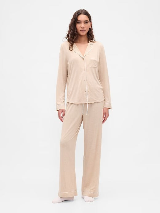 Woman wearing a beige pajama set on a white background